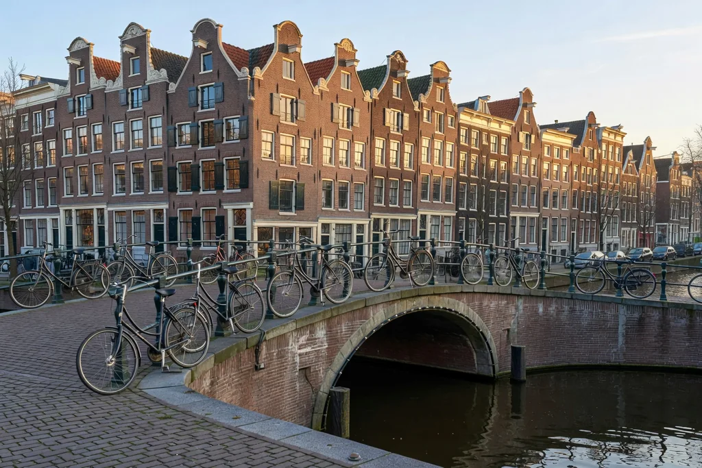 Amsterdam canal with historic gabled houses, bicycles on a bridge and soft morning light