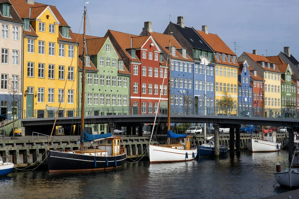 Copenhagen harbour with colourful old townhouses, moored boats and a modern bridge