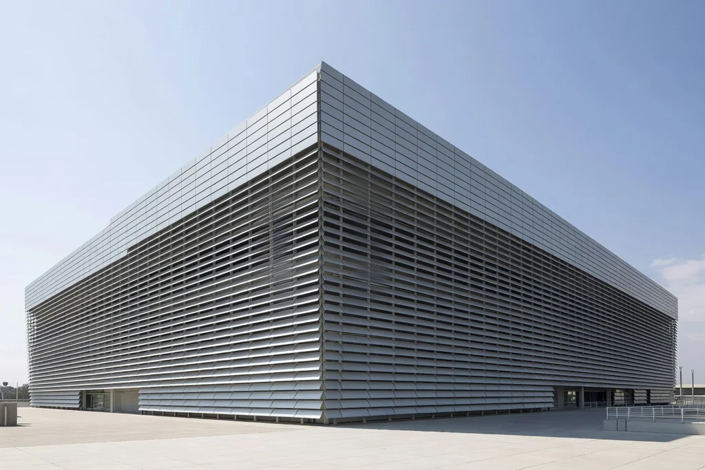 Modern Spanish football stadium clad in reflective steel louvres, clean exterior in bright daylight